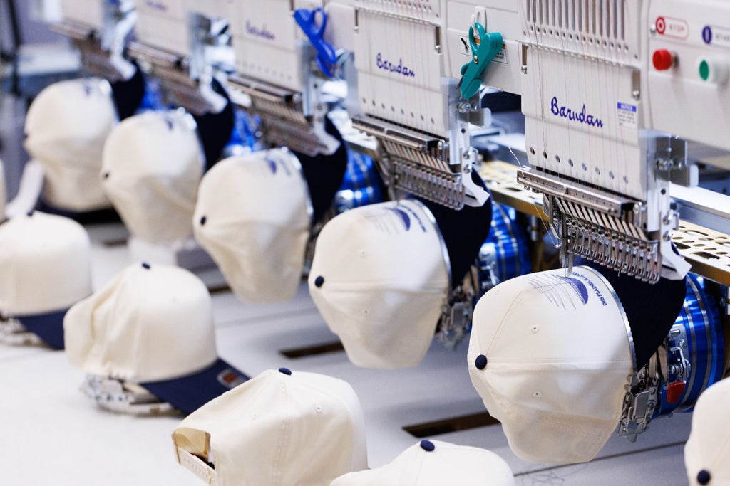 Embroidery machine with multiple heads working on fabric pieces.